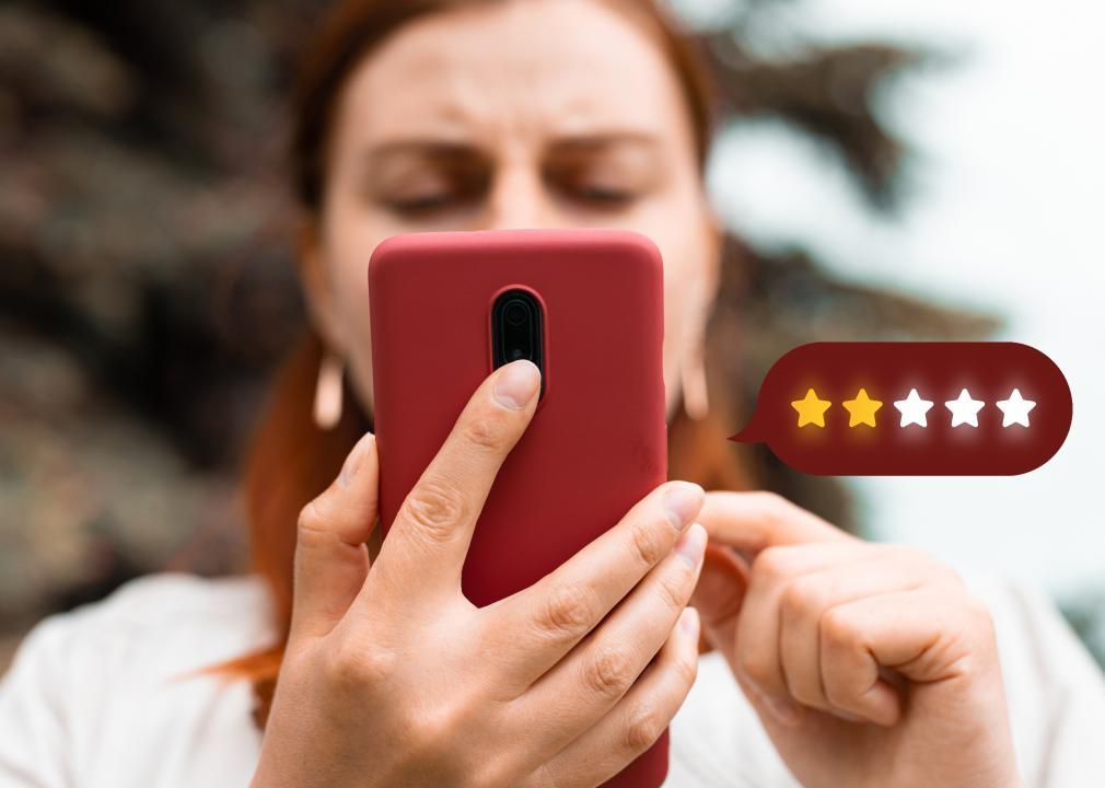 A woman holds a cell phone with 2 out of 5 stars appearing on the right-hand side.
